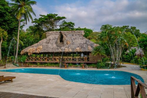 un complejo con un edificio con techo de paja y una piscina en Banana Palms Hotel en Río Dulce