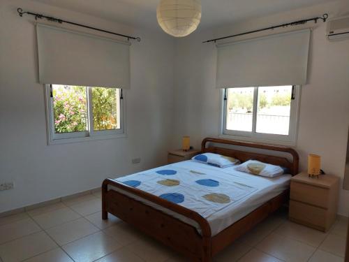 ein Schlafzimmer mit einem Bett und zwei Fenstern in der Unterkunft Pyla Palms Resort B1 - 1 in Larnaka