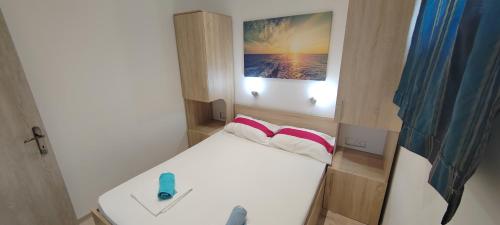 a small room with a bed and a picture on the wall at Apartmani ANDRIJA in Živogošće