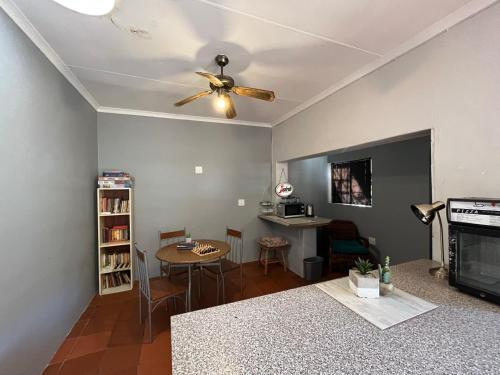 a living room with a ceiling fan and a table at Casa Bravo - Pilgrims Palace in Pretoria