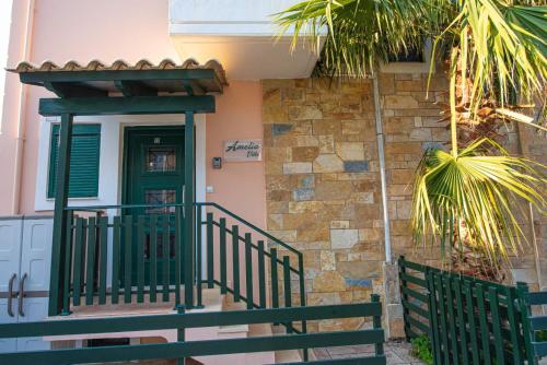 a house with a green door and a green railing at Amelia Villa in Nikiana