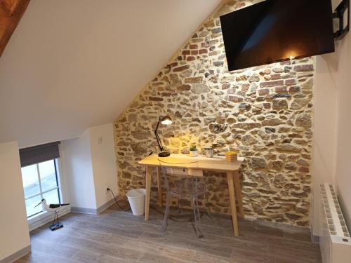 einen Holztisch in einem Zimmer mit einer Steinmauer in der Unterkunft La Salorge in Séné