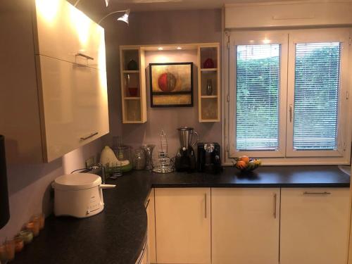 a kitchen with white cabinets and a black counter top at Hyper centre - Balcon / Parking in Le Havre