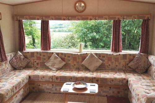 um sofá numa sala de estar com uma grande janela em Hedgehog Holiday Home in the countryside, 10 mins to Lligwy beach em Llandyfrydog