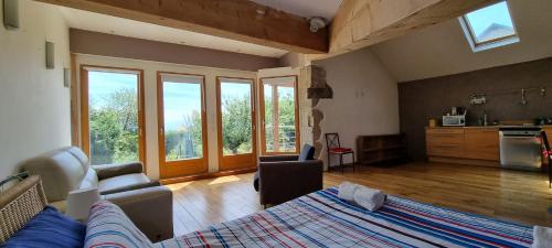 - un salon avec un lit, un canapé et des fenêtres dans l'établissement Au vieux four à pain - Studio à louer, à Chevry