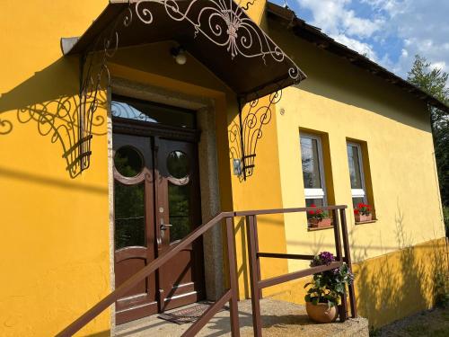 a yellow house with a door and a porch at Chata U Skota in Janov nad Nisou