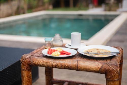 Join Homestay في كوتا لومبوك: طاولة مع طبقين من الطعام بجوار حمام سباحة