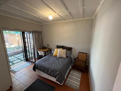 a bedroom with a bed and a table and a window at Casa Bravo - Pilgrims Palace in Pretoria