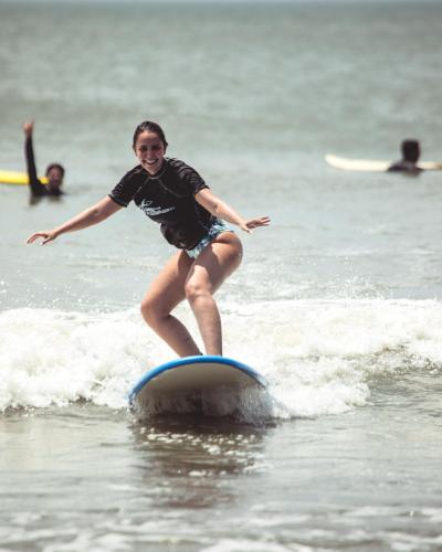 a woman riding a wave on a surfboard in the ocean at Manglar Lodge in San Carlos