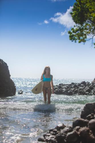 a woman is standing in the water with a surfboard at Manglar Lodge in San Carlos