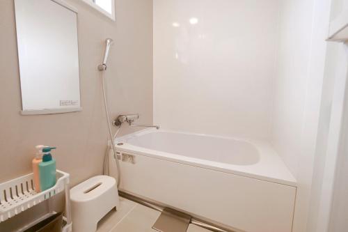 a bathroom with a tub and a toilet and a sink at Panda Stay Okayama in Okayama