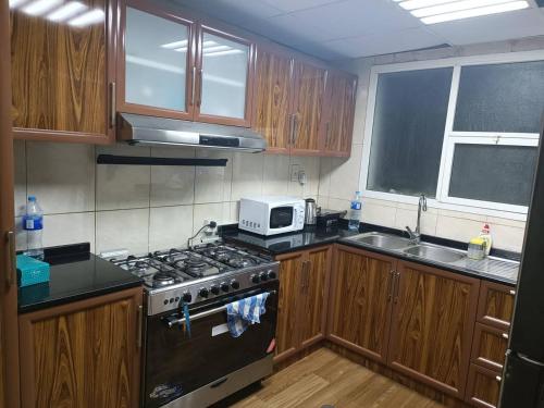 a kitchen with a stove and a microwave at شقة كبيرة وفخمة large and luxury two bedroom in Ajman 