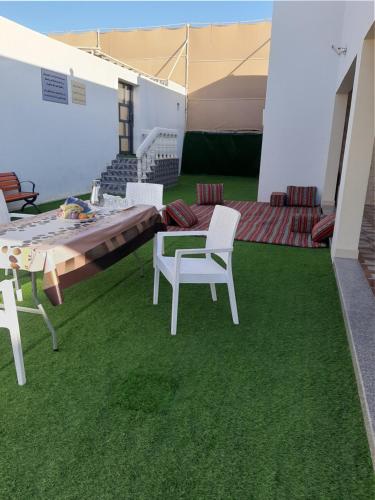 un patio con mesa y sillas sobre hierba en استراحه الولايه en Salalah