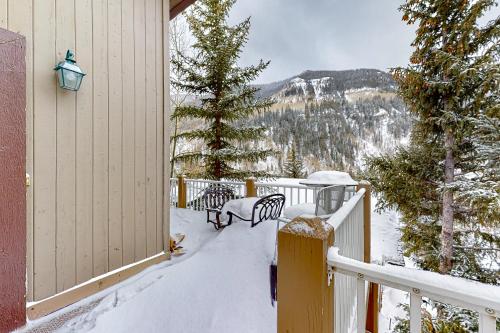 a snowy balcony with two benches and a tree at Spruce Way Retreat in Vail