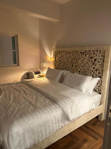a bedroom with a white bed with a wooden headboard at Dar Sayang in Taif
