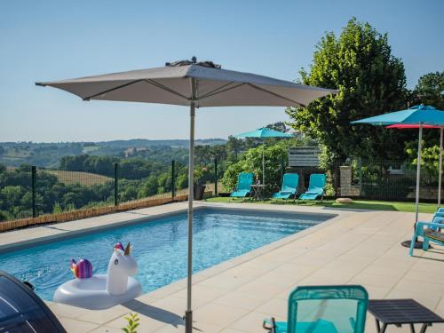 une piscine avec un parasol et un cheval jouet dans un flotteur dans l'établissement Chez Hélene, à Sarlat-la-Canéda