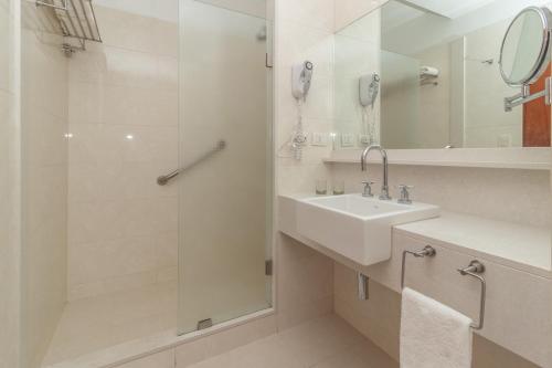 a white bathroom with a sink and a shower at Hotel Faranda Express Puerta del Sol Porlamar in Porlamar