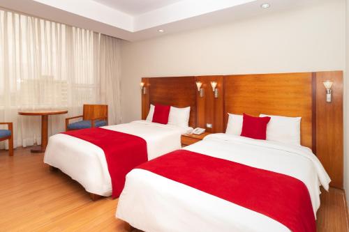 two beds in a hotel room with red and white sheets at Hotel Faranda Express Puerta del Sol Porlamar in Porlamar