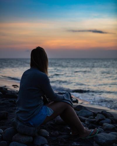 a woman sitting on the beach watching the sunset at Manglar Lodge in San Carlos