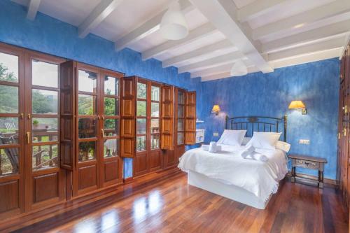 a bedroom with a bed with blue walls and windows at Vivienda Vacacional La Cortina in Meré