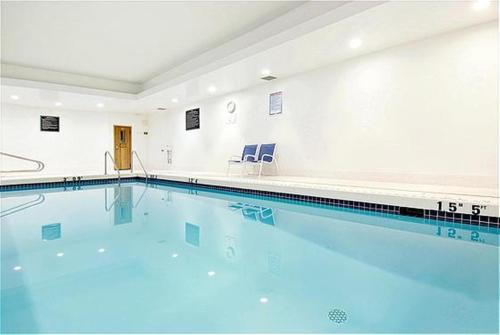 a large swimming pool with two blue chairs in it at Holiday Inn Express and Suites Surrey by IHG in Surrey