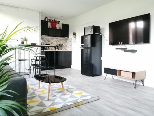 eine Küche mit einem schwarzen Kühlschrank und einem Tisch in der Unterkunft LE BIKING *STUDIO (30m²) *WIFI*PARKING PRIVE*CALME in Lourdes