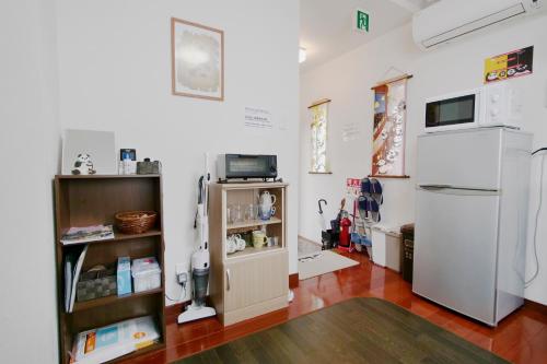 Cette chambre comprend un réfrigérateur et une étagère avec un réfrigérateur. dans l'établissement Panda Stay Okayama, à Okayama