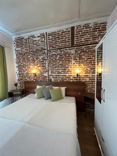 1 dormitorio con cama blanca y pared de ladrillo en Macide Hanım Konağı, en Ayvalık