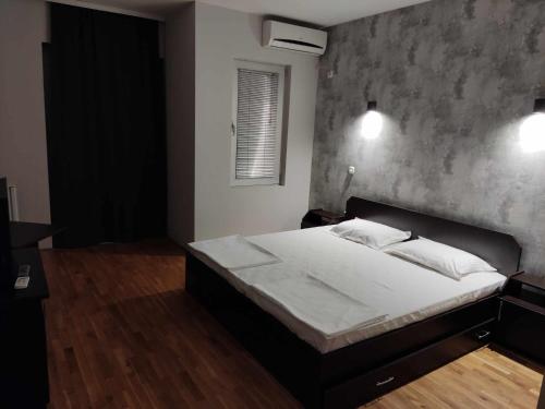 1 dormitorio con 1 cama grande y pared de hormigón en Apartments Philip II, en Ohrid