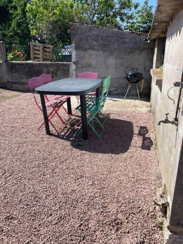 stół i trzy krzesła siedzące obok grilla w obiekcie Chez Mélanie maison proximité du Pal w mieście Neuilly-le-Réal