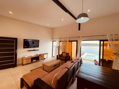 a living room with a couch and a table and a tv at Villa Assinie Bord de Lagune in Assinie