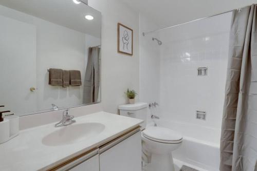 a white bathroom with a toilet and a sink at Elegant Condo with Gorgeous Views at Crystal City in Arlington