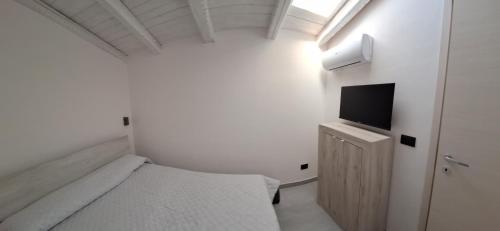 een kleine witte slaapkamer met een bed en een televisie bij Luxury home 2 in Siracusa