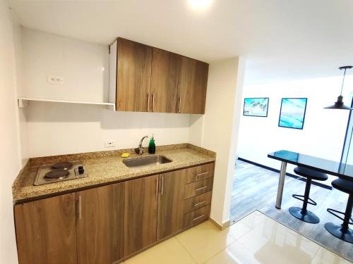 cocina con armarios de madera, fregadero y mesa en 8 Apartaestudio Cedritos independiente, en Bogotá