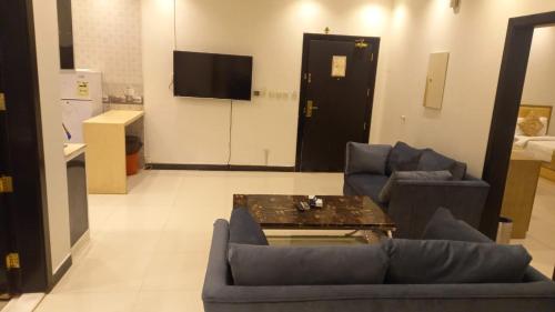 uma sala de estar com um sofá, uma mesa e uma televisão em Quiet Rooms 1 em Riyadh