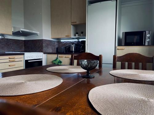 a kitchen with a wooden table with four chairs and a kitchen with at Ylimmän kerroksen kaksio Varkaudessa in Varkaus