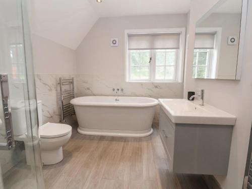 a bathroom with a tub and a toilet and a sink at 1 Golf Links Cottages in Northwich