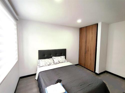 Schlafzimmer mit einem Bett und einem Holzschrank in der Unterkunft 8 Apartaestudio Cedritos independiente in Bogotá