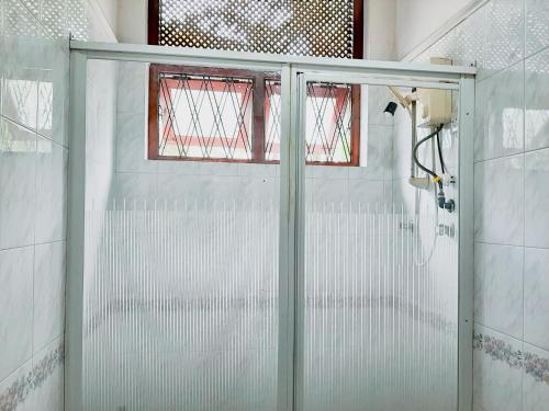 a shower with a glass door in a bathroom at Marette Holiday Bungalow in Moratuwa