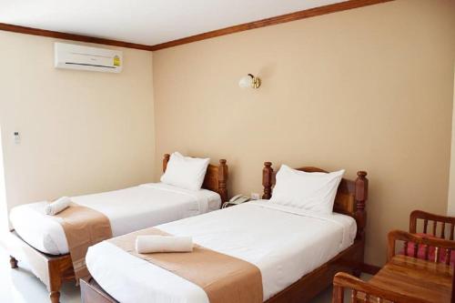 Cette chambre comprend 2 lits et une chaise. dans l'établissement NP Residence, à Nakhon Phanom