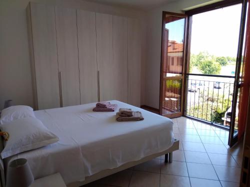 Un dormitorio con una cama blanca con toallas. en Flat Garda, en Cavalcaselle