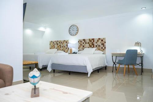 1 dormitorio con 2 camas, mesa y reloj en Hotel Zima, en San Isidro