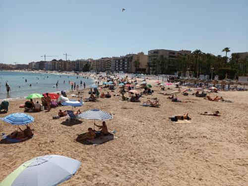 a crowd of people on a beach with umbrellas at Duquesa Beach in Torrevieja