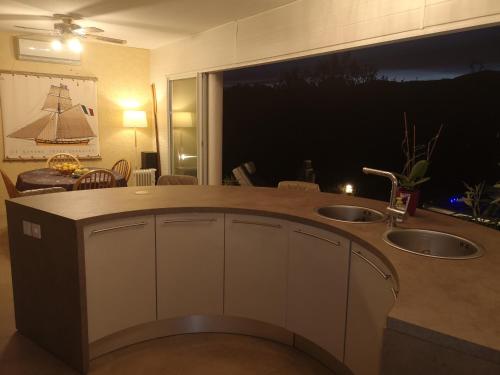 une cuisine avec deux lavabos et une grande fenêtre dans l'établissement Villa les pieds dans l'eau, à Le Pont du Travo