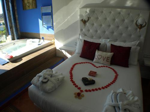 a bed with a heart made out of towels and a bath tub at Suite Rural Carenas in Carenas