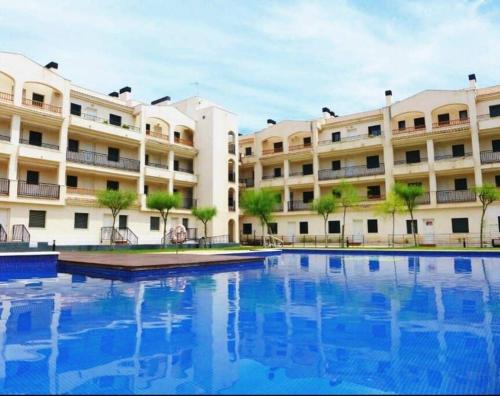 a large building with a swimming pool in front of it at Ático con acceso directo al mar in Miami Platja