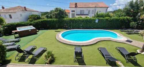 a backyard with a swimming pool and chairs on the grass at Apartments Stengl in Rab