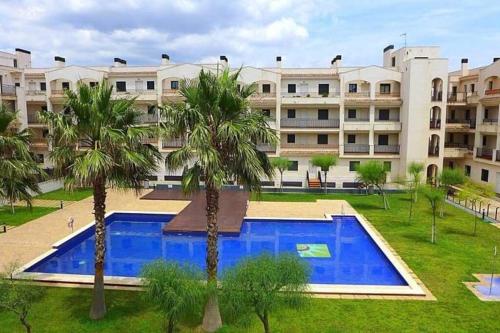 an apartment complex with a swimming pool and two palm trees at Ático con acceso directo al mar in Miami Platja