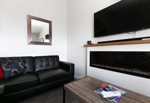 a living room with a black leather couch and a fireplace at Eagle's View Penthouse in Victoria