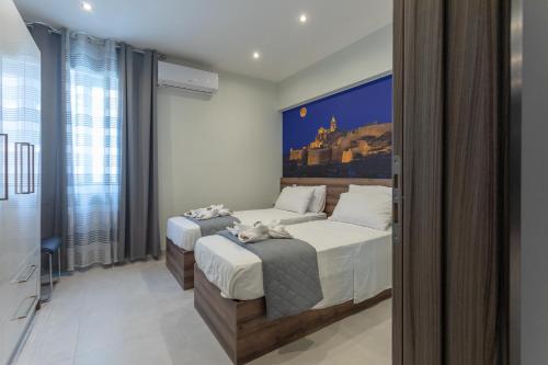 a bedroom with two beds and a large window at Red Rose in Marsalforn